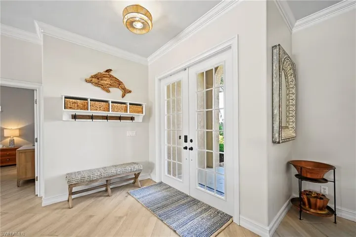 Mudroom with ornamental molding, light wood-type flooring, and french doors