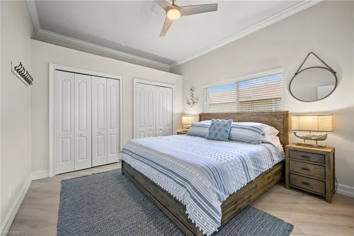 Bedroom with two closets, ceiling fan, and crown molding
