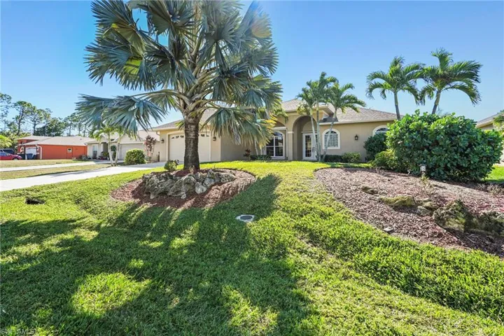 View of front of property with a garage, stucco siding, concrete driveway, and a front yard