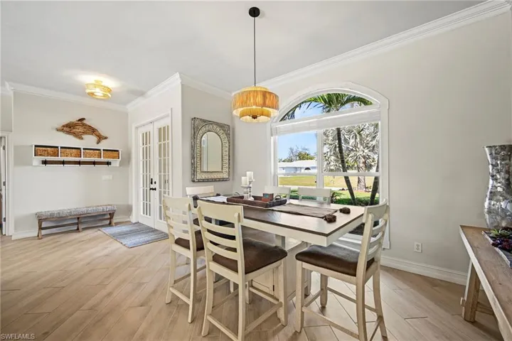 Dining area featuring french doors, light wood finished floors, and ornamental molding