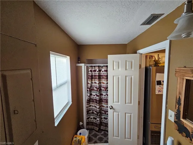 Entrance foyer with a textured ceiling and visible vents