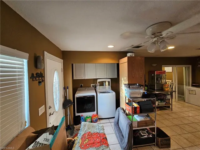 Laundry area featuring ceiling fan, laundry area, light tile patterned floors, and washer and clothes dryer