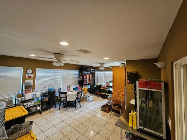 Dining area with light tile patterned floors, a textured ceiling, visible vents, and a ceiling fan