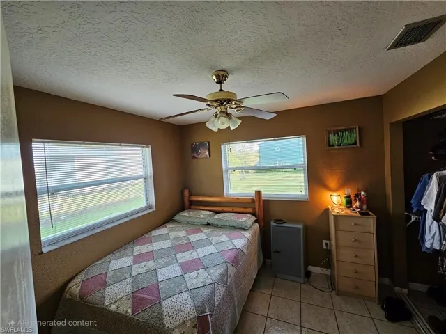 Bedroom with a ceiling fan, light tile patterned flooring, a textured ceiling, and visible vents