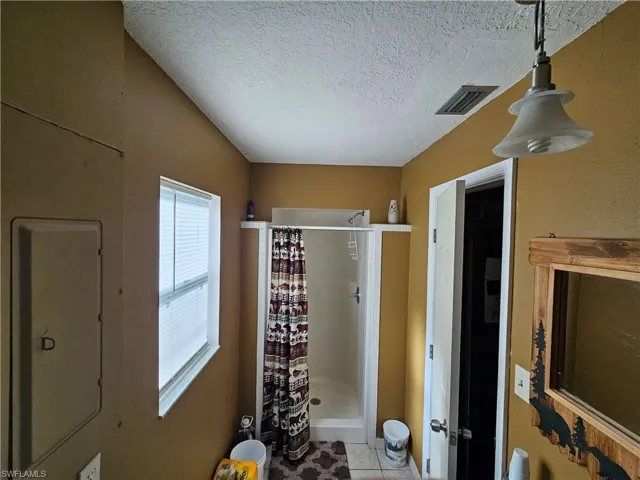 Full bath featuring a shower stall, visible vents, tile patterned flooring, and a textured ceiling