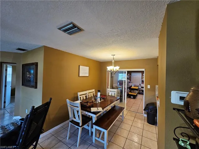Dining room with light tile patterned flooring, a notable chandelier, and visible vents