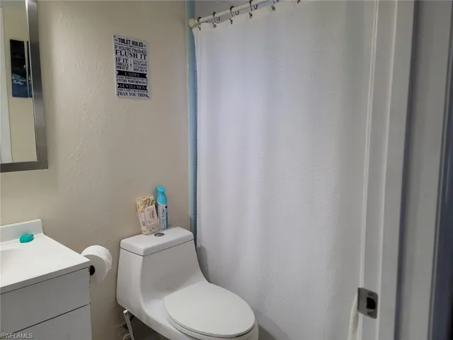 Full bath featuring a textured wall, vanity, and curtained shower