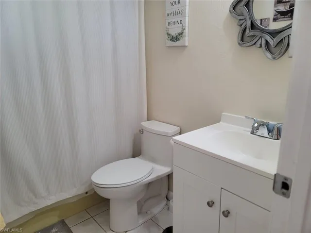 Full bathroom with vanity, a shower with curtain, and light tile patterned floors