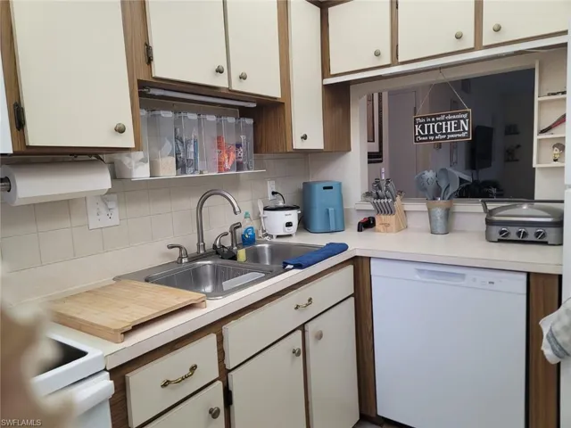 Kitchen featuring dishwasher, light countertops, decorative backsplash, and dual tone cabinetry