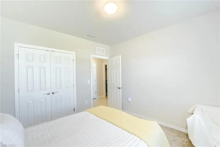 Bedroom with baseboards, light carpet, a closet, and visible vents