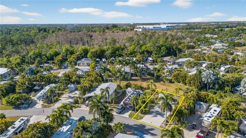Aerial view of residential area with property parcel outlined and a forest