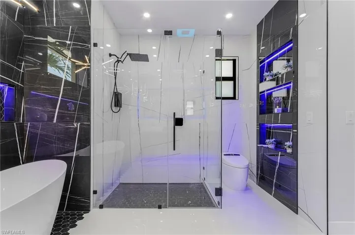 Bathroom with a marble finish shower, toilet, recessed lighting, a soaking tub, and tile walls