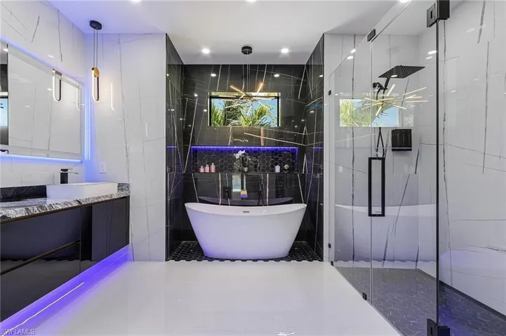 Full bath with a soaking tub, vanity, tile walls, and a shower stall