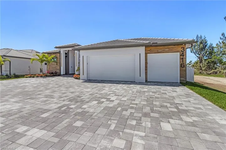 View of front of home featuring decorative driveway, an attached garage, and a tiled roof