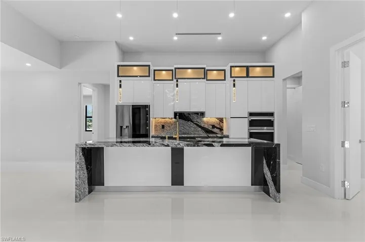 Kitchen featuring a large island, white cabinets, appliances with stainless steel finishes, modern cabinets, and backsplash