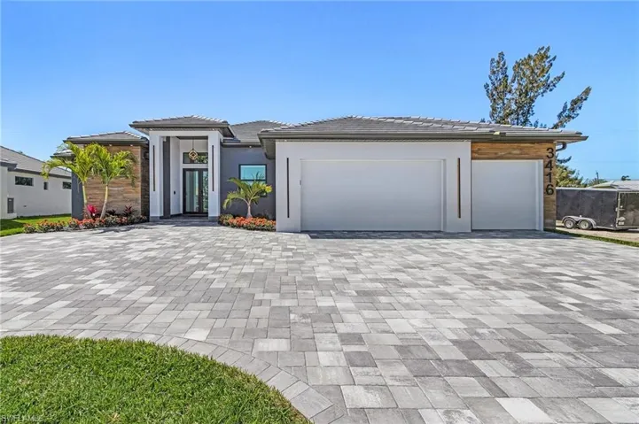 View of front of house with decorative driveway, a garage, a tile roof, and stucco siding