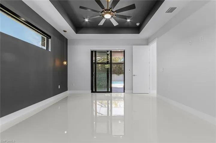 Spare room featuring visible vents, baseboards, a raised ceiling, and a ceiling fan