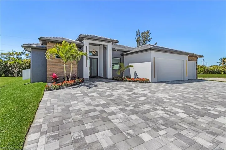 Prairie-style home featuring stucco siding, an attached garage, decorative driveway, and a front lawn