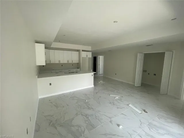 Unfurnished living room featuring a raised ceiling and light tile flooring