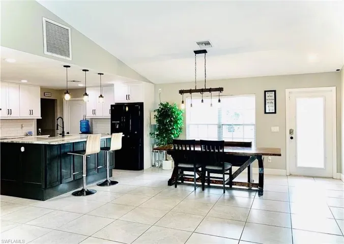 Kitchen with dark cabinets, recessed lighting, freestanding refrigerator, pendant lighting, and light tile patterned flooring