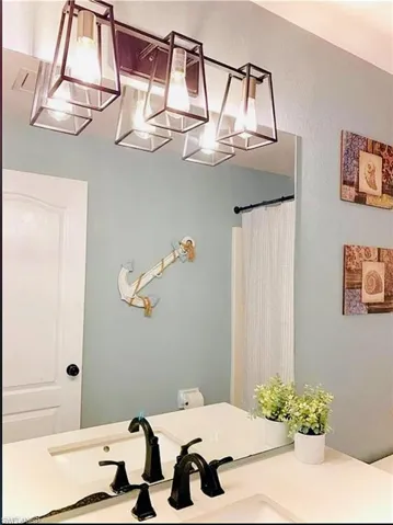 Bathroom with a chandelier, vanity, and a shower with shower curtain