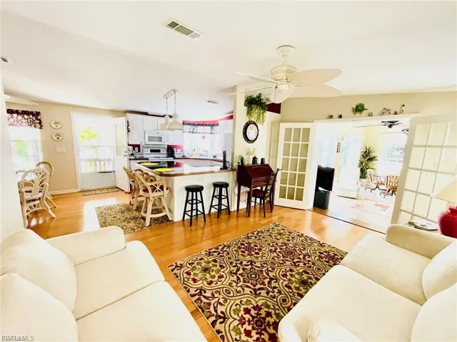 Living area with french doors, light wood-style flooring, and a ceiling fan