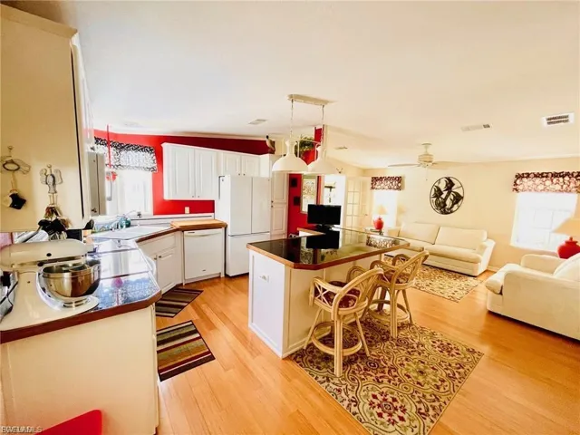 Kitchen featuring white cabinetry, healthy amount of natural light, white appliances, a center island, and vaulted ceiling