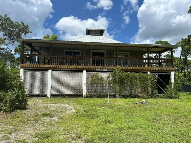 Front view of house with a lawn and a wooden deck
