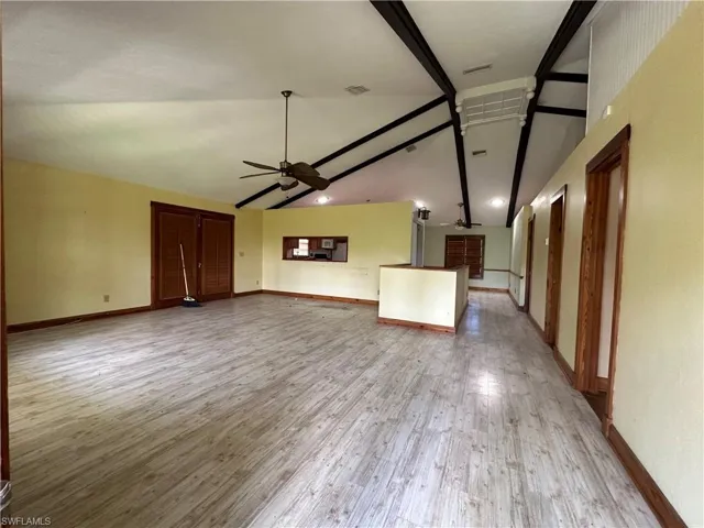 Unfurnished living room with beamed ceiling, high vaulted ceiling, light wood-type flooring, and ceiling fan