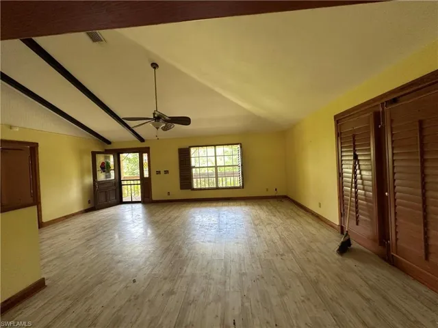 Unfurnished bedroom featuring vaulted ceiling with beams and light wood-type flooring