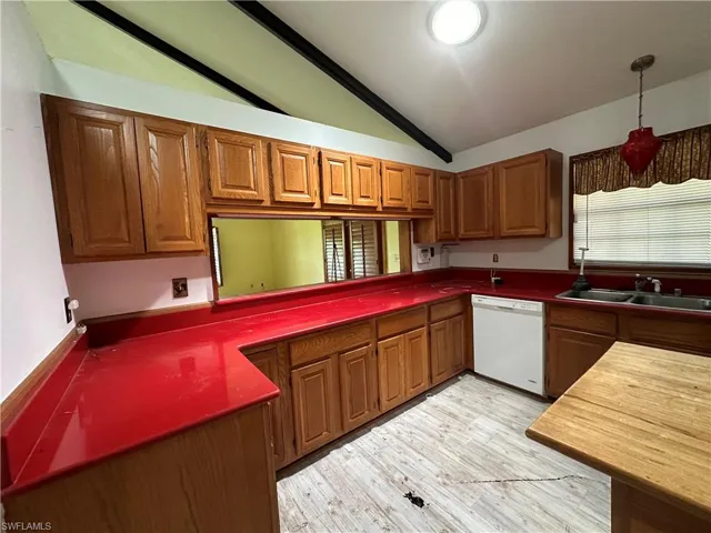 Kitchen featuring light hardwood / wood-style flooring, white dishwasher, sink, hanging light fixtures, and lofted ceiling