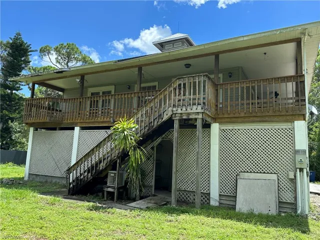 Front view of house with a wooden deck and a lawn