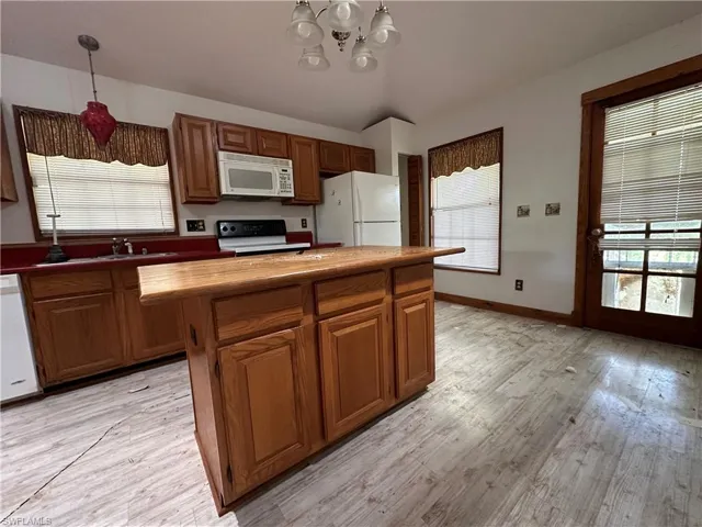 Kitchen Island with light hardwood / wood-style flooring, plenty of natural light, and white appliances