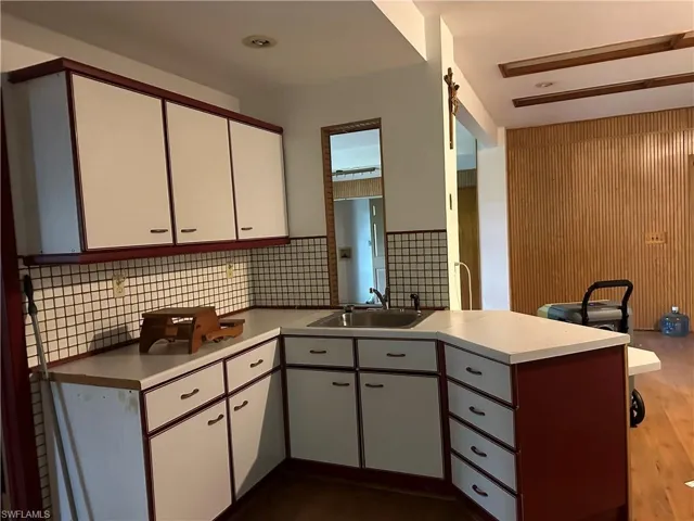 Downstairs Kitchen featuring hardwood / wood-style flooring, backsplash, sink, and kitchen peninsula