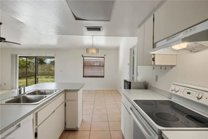 Kitchen featuring pendant lighting, sink, white appliances, white cabinets, and light tile patterned flooring