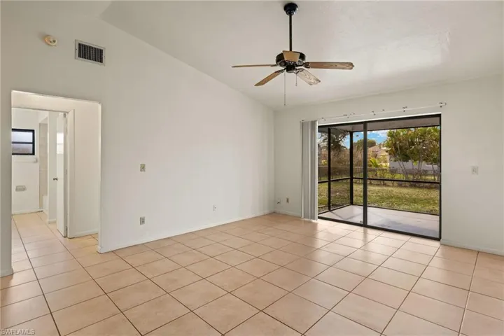 Tiled empty room featuring ceiling fan and high vaulted ceiling