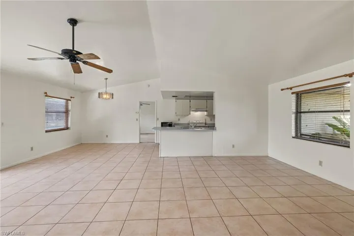 Unfurnished living room with light tile patterned flooring, ceiling fan, and lofted ceiling