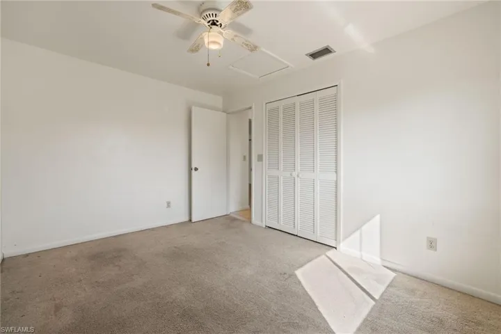 Unfurnished bedroom with ceiling fan, a closet, and light carpet