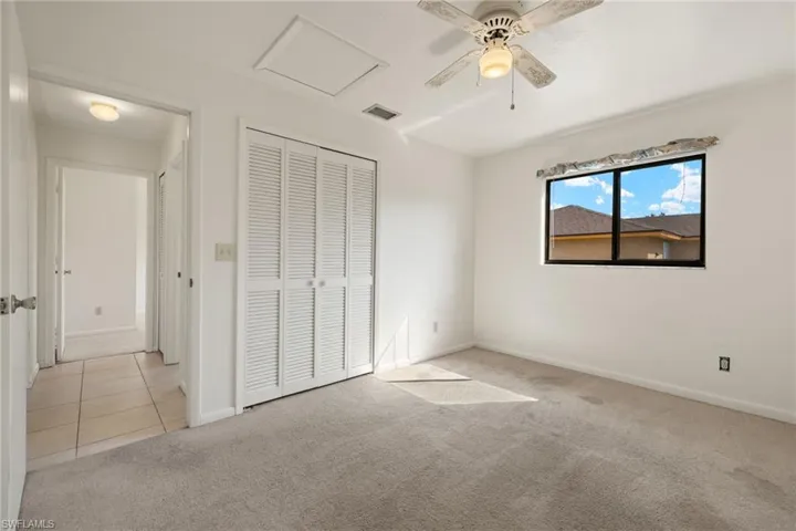 Unfurnished bedroom featuring light colored carpet, ceiling fan, and a closet