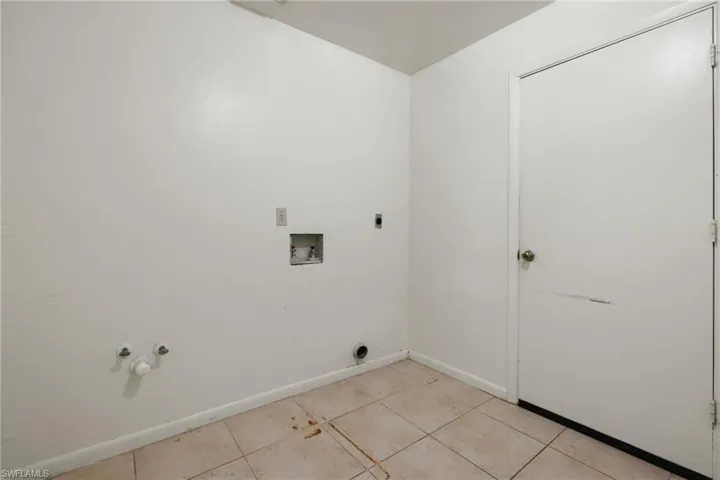 Washroom with washer hookup, hookup for a gas dryer, electric dryer hookup, and light tile patterned flooring