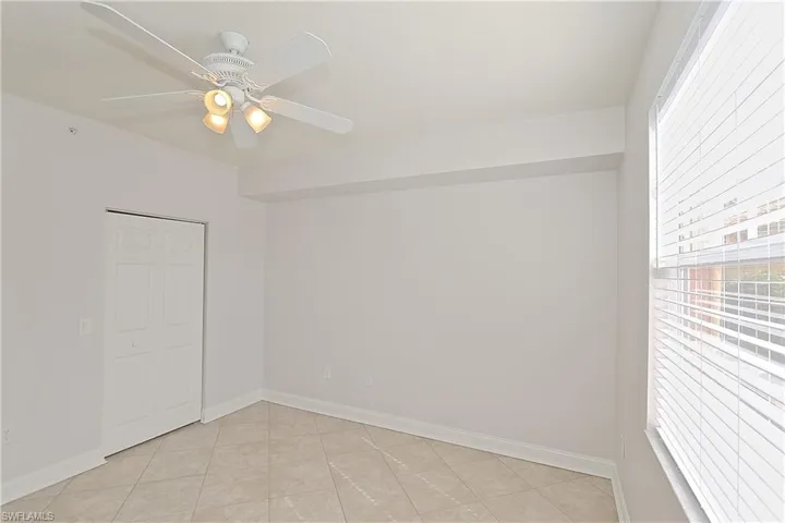 Unfurnished room featuring healthy amount of natural light, a ceiling fan, and light tile patterned floors