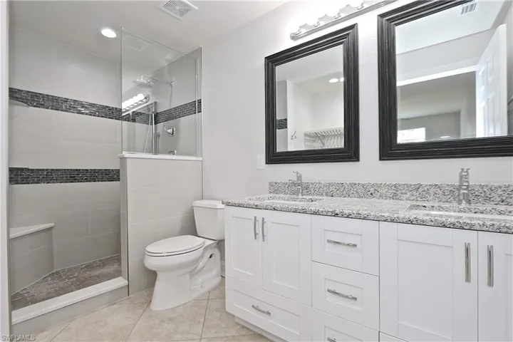 Full bath featuring double vanity, walk in shower, tile patterned flooring, and recessed lighting