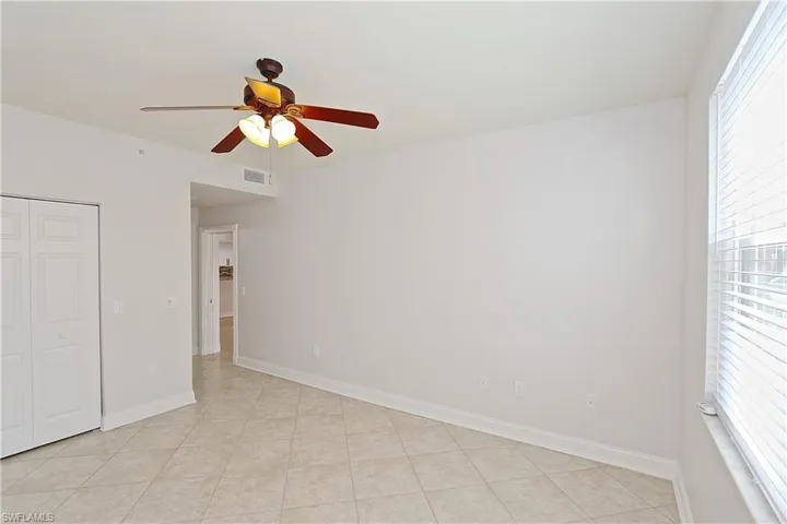 Unfurnished bedroom featuring a ceiling fan, a closet, and light tile patterned flooring