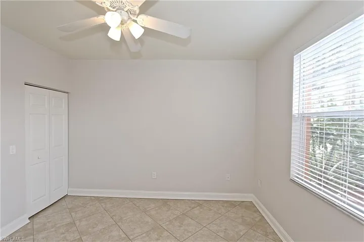 Unfurnished bedroom with light tile patterned floors, a ceiling fan, and a closet