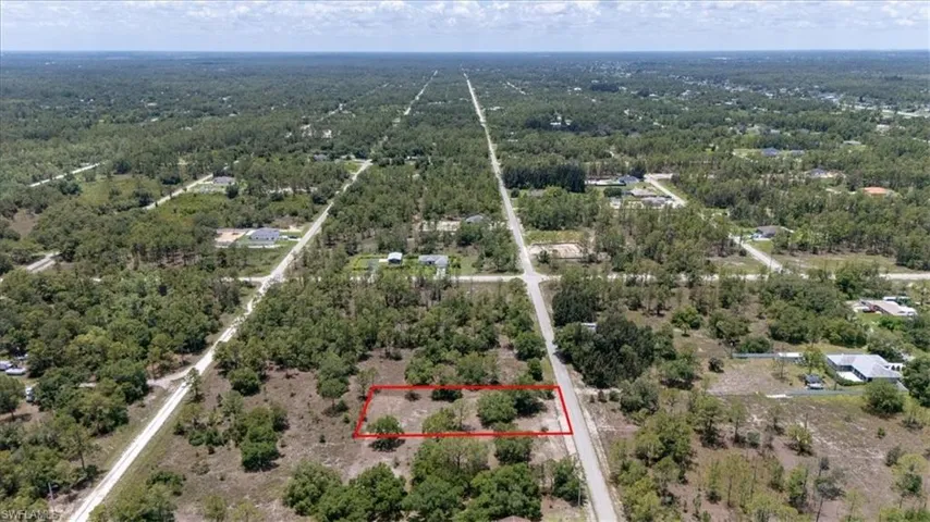 Aerial view of property and surrounding area featuring property parcel outlined and a forest