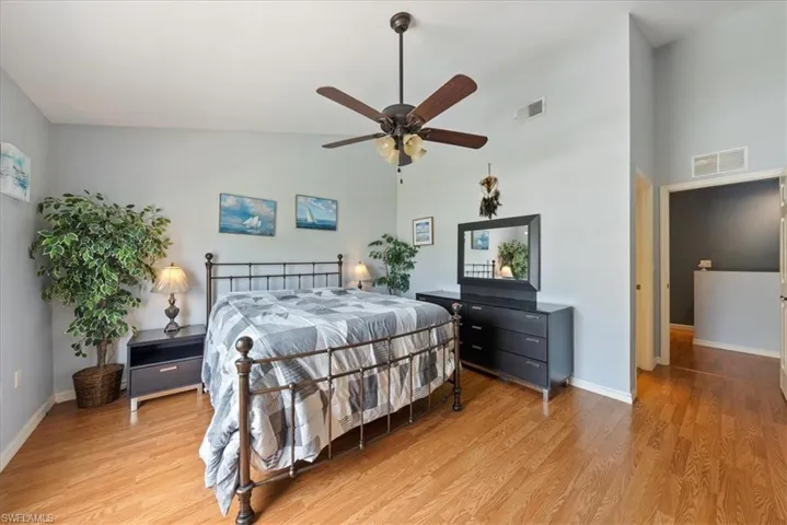 Bedroom featuring baseboards, light wood-style flooring, visible vents, and high vaulted ceiling