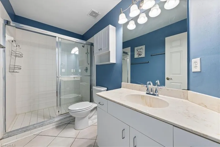 Full bath featuring a stall shower, toilet, visible vents, tile patterned flooring, and vanity