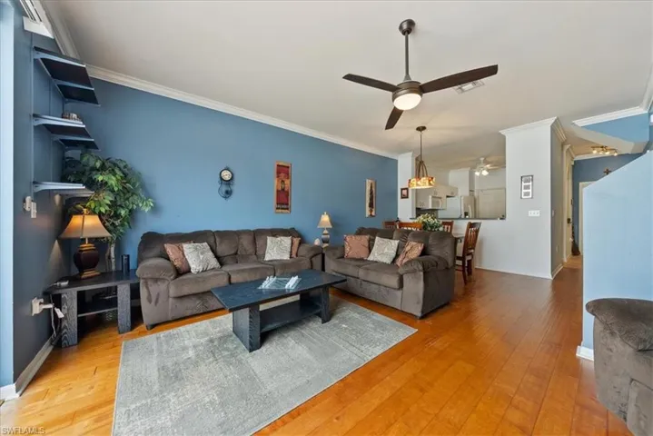 Living area featuring ceiling fan, ornamental molding, light wood finished floors, and visible vents