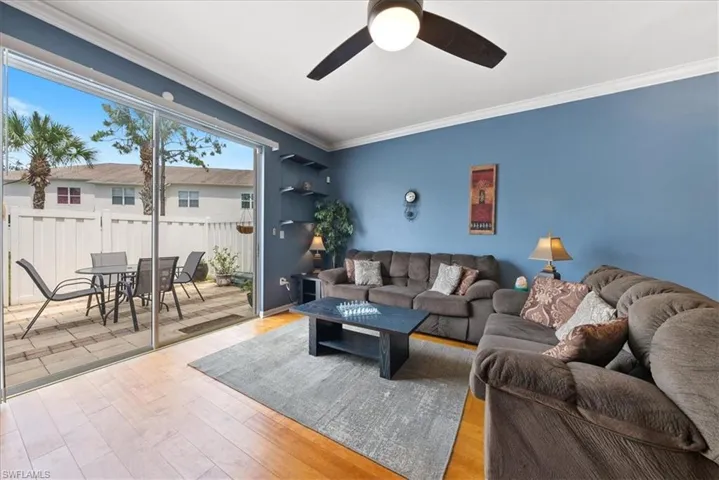 Living room featuring ornamental molding, ceiling fan, and wood finished floors