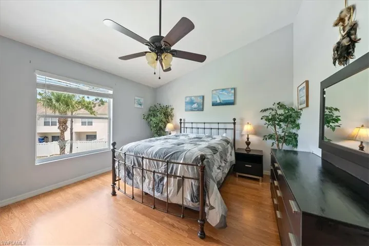 Bedroom with baseboards, vaulted ceiling, ceiling fan, and wood finished floors